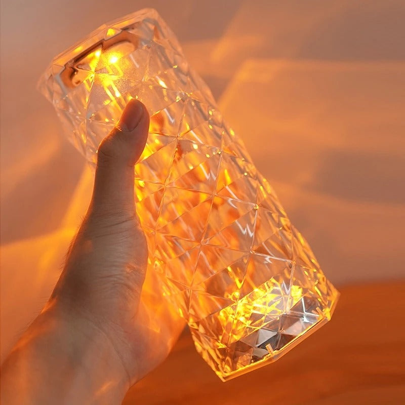 Mão segurando luminária de LED em cristal transparente com luz amarela aconchegante