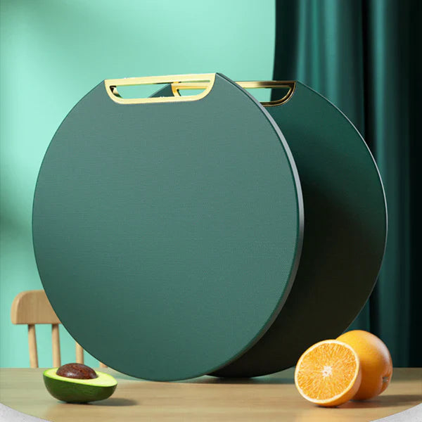 Mesa de madeira com mesa lateral redonda verde escura com alça dourada, abacate cortado e laranja inteira