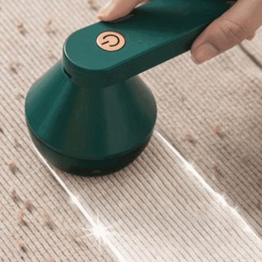 Aspirador portátil verde sendo usado para limpar migalhas em tecido claro