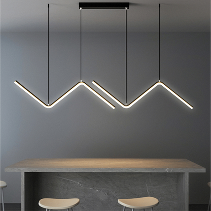 Luminária pendente LED moderna em formato zig-zag acima de bancada de pedra com cadeiras minimalistas