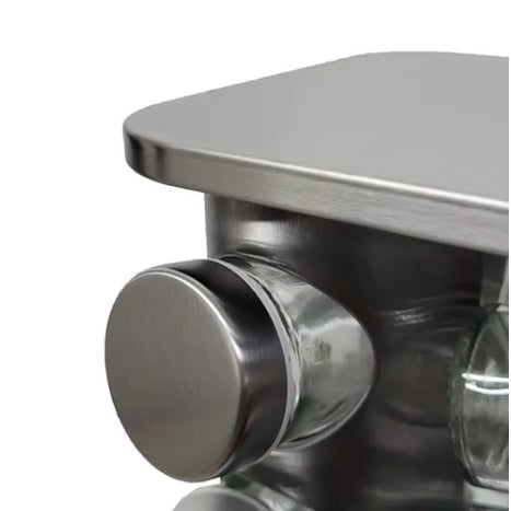 Canto inferior de uma mesa de aço inox com acabamento escovado, mostrando um botão circular metálico
