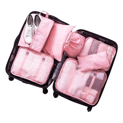 Mala preta organizada com bolsas de viagem rosa e tênis branco para planejamento de viagem