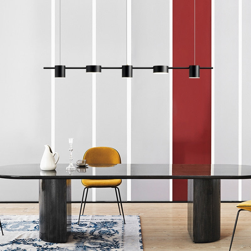 Sala de jantar minimalista com mesa preta, cadeiras amarelas, luminária preta e parede com faixa vermelha