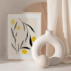 Vaso branco circular decorativo com bola e quadro minimalista de folhas e limões amarelos