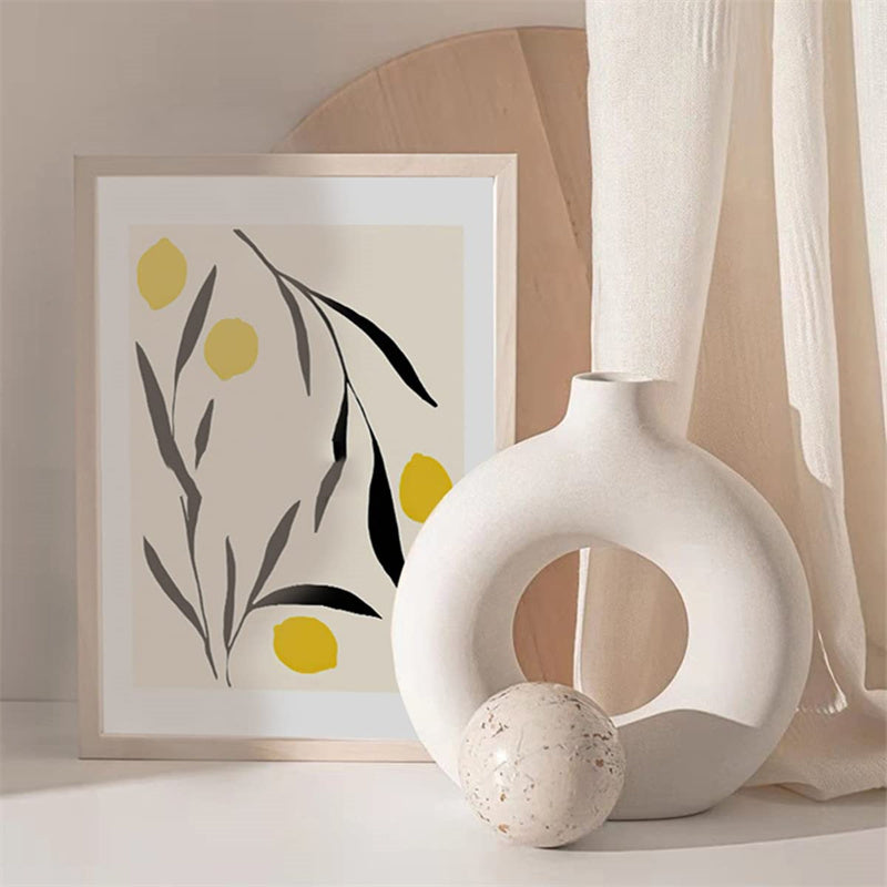 Vaso branco circular decorativo com bola e quadro minimalista de folhas e limões amarelos