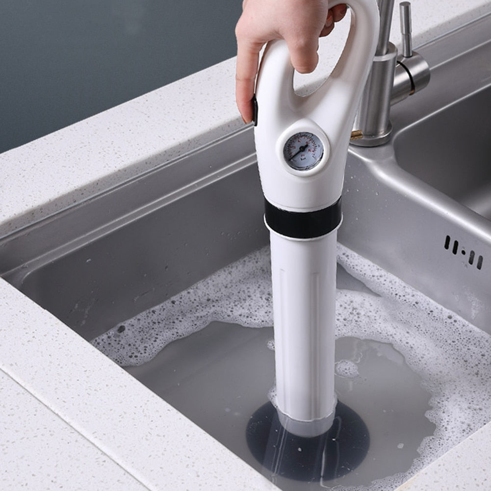 Mão usando desentupidor de pia branco com manômetro em pia de cozinha inox