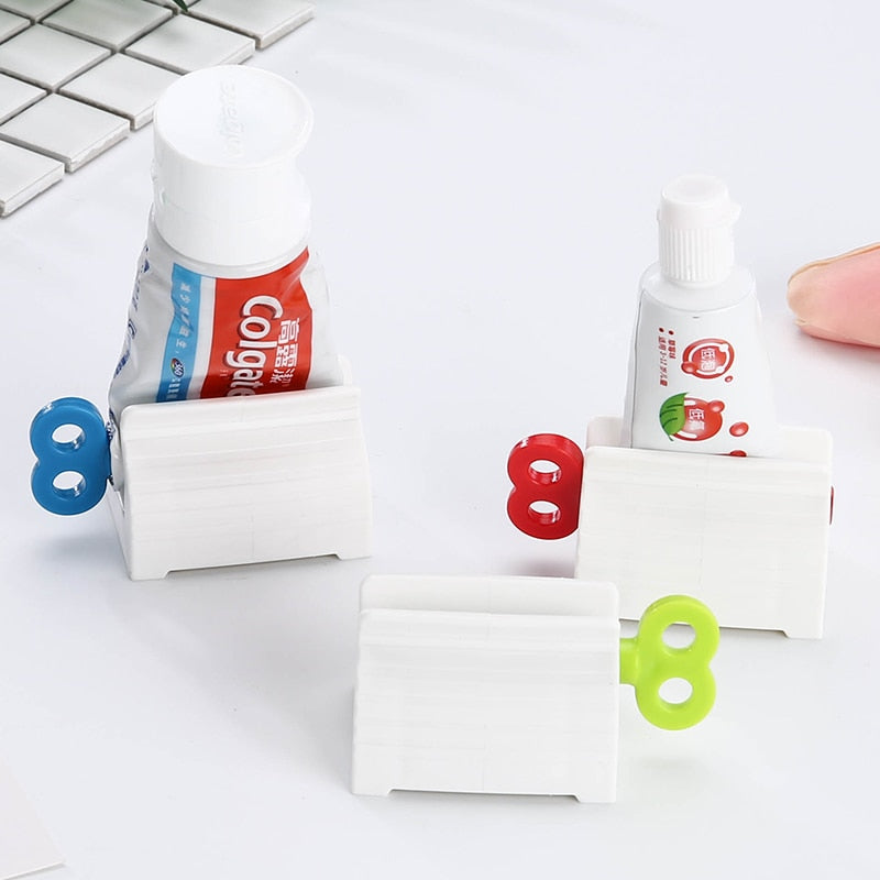 Suportes brancos para espremer tubos de pasta de dente com chaves coloridas em azul, vermelho e verde