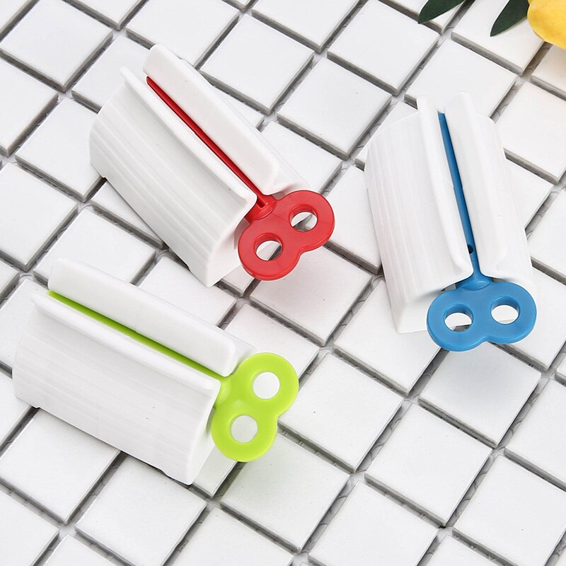 Três prendedores de saco plásticos brancos com fechos coloridos vermelho, azul e verde sobre superfície de azulejos brancos