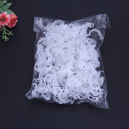 Saco transparente com argolas plásticas brancas para cortina em fundo preto com flor rosa
