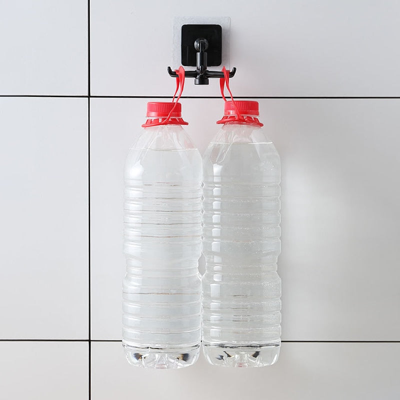 Duas garrafas plásticas transparentes com tampa vermelha cheias de água penduradas em gancho preto em parede branca com azulejos