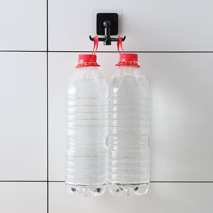 Duas garrafas plásticas transparentes com tampa vermelha cheias de água penduradas em gancho preto em parede branca com azulejos