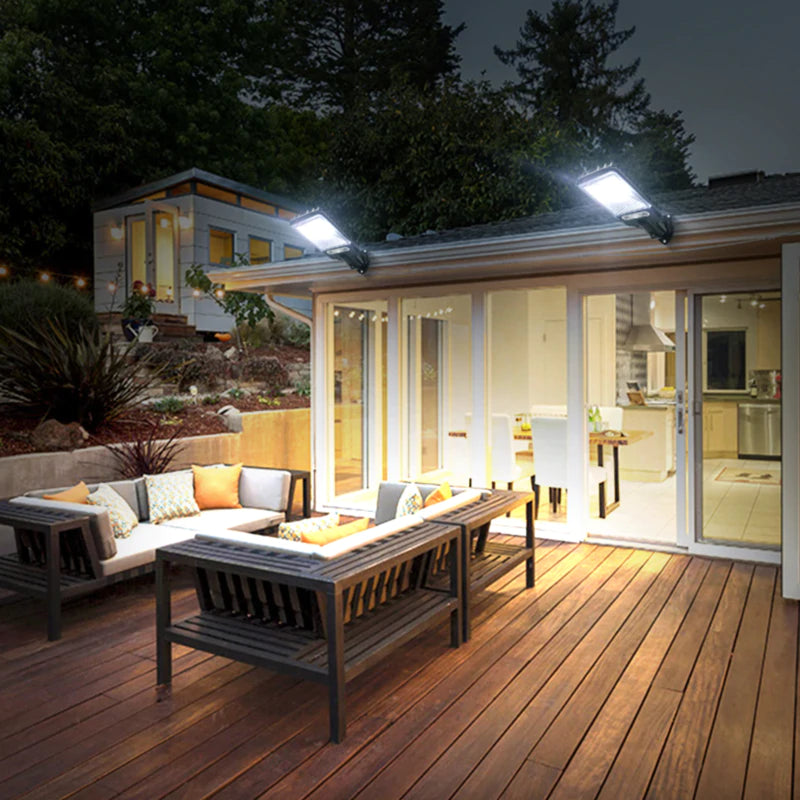 Área externa iluminada à noite com refletores solares LED e móveis de madeira com almofadas coloridas