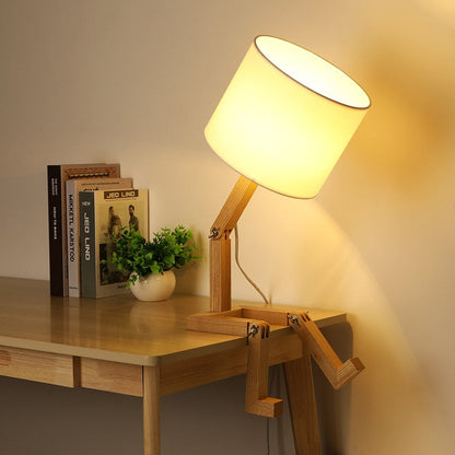 Abajur de madeira articulado com cúpula branca em mesa com livros e vaso decorativo