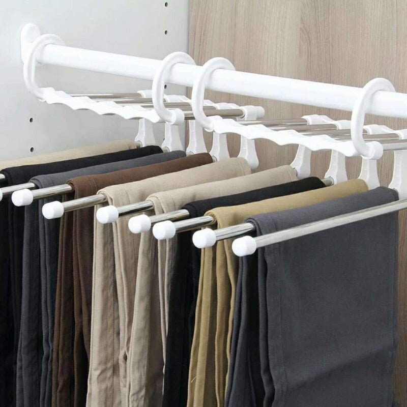Suporte de cabides branco com barras metálicas organizando calças em diferentes cores em armário moderno