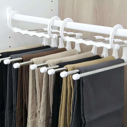 Suporte de cabides branco com barras metálicas organizando calças em diferentes cores em armário moderno