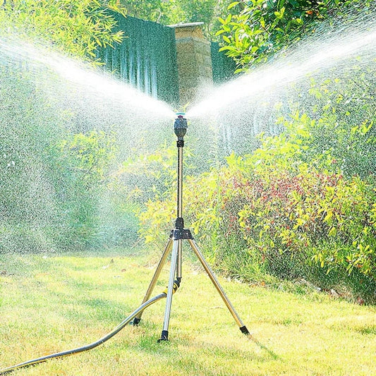 Aspersor de jardim em tripé irrigando grama e arbustos sob luz solar forte