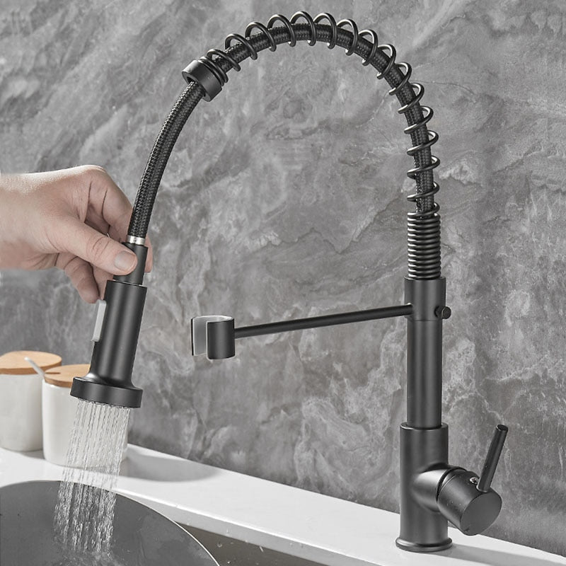 Torneira de cozinha preta com bico flexível e água corrente, parede cinza de fundo