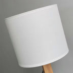 Abajur de mesa com cúpula branca e base de madeira clara em fundo cinza