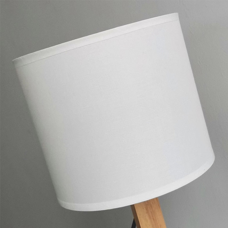 Abajur de mesa com cúpula branca e base de madeira clara em fundo cinza