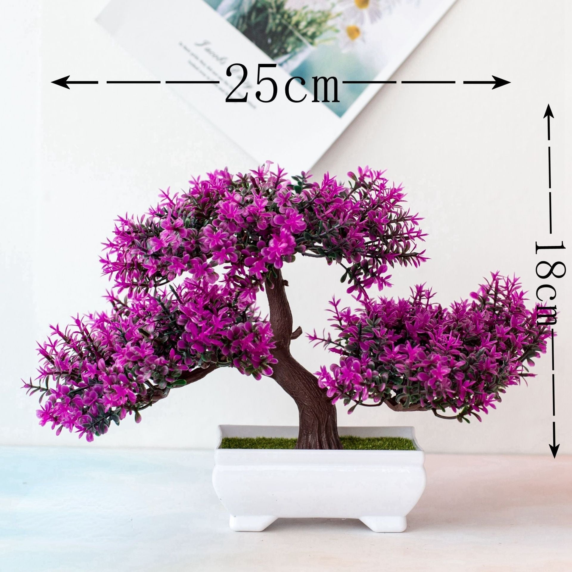 Bonsai artificial com flores roxas em vaso branco, medindo 25 cm de largura por 18 cm de altura