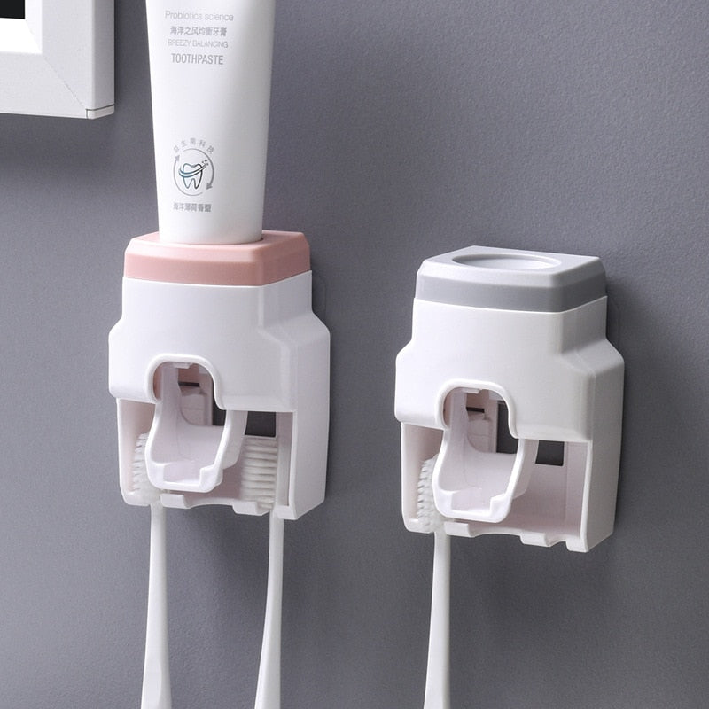 Dispenser automático de pasta de dente com suporte para escovas, design moderno branco com detalhes em rosa e cinza, fixado na parede