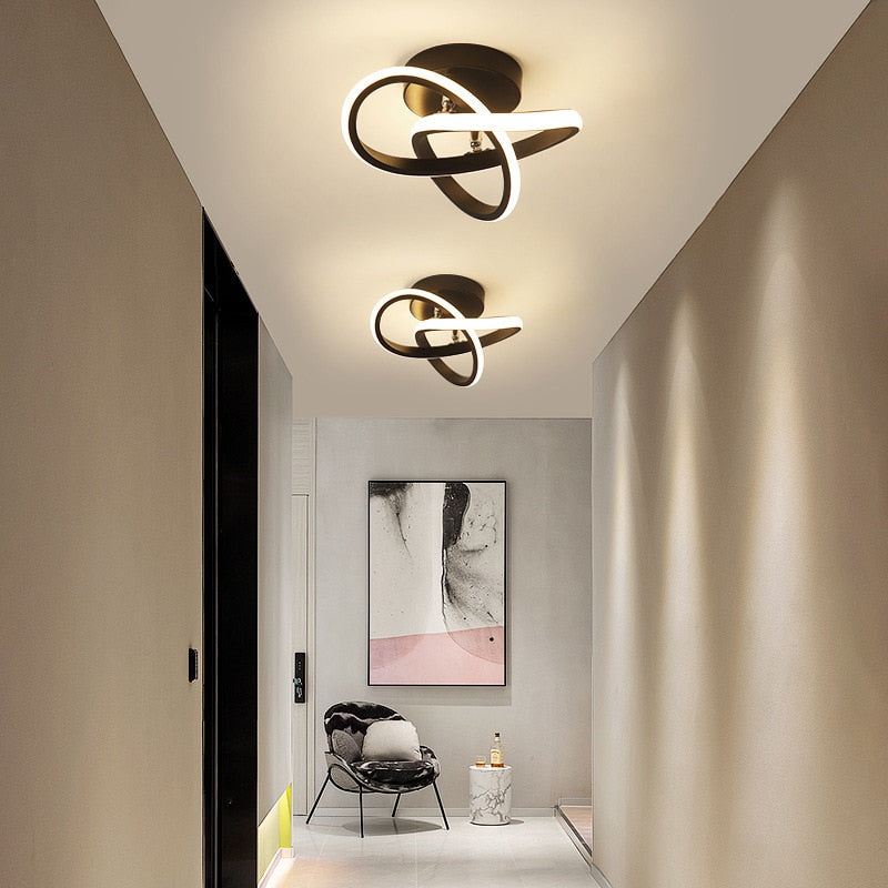 Corredor moderno com luminárias de teto LED em design orgânico, cadeira estofada e quadro abstrato na parede