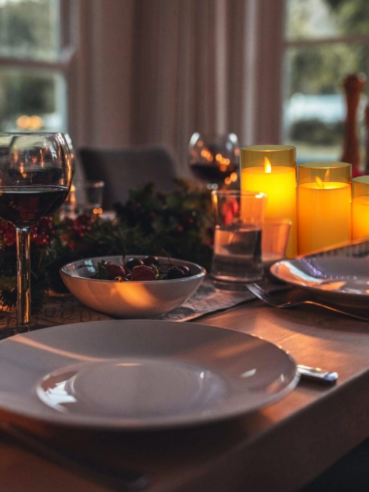 Jantar romântico com velas acesas, taças de vinho e bowl de frutas em mesa decorada