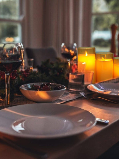 Jantar romântico com velas acesas, taças de vinho e bowl de frutas em mesa decorada