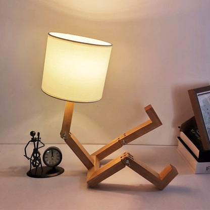 Abajur com design de madeira articulada em forma de pessoa sentado, luz quente, relógio e escultura ao fundo