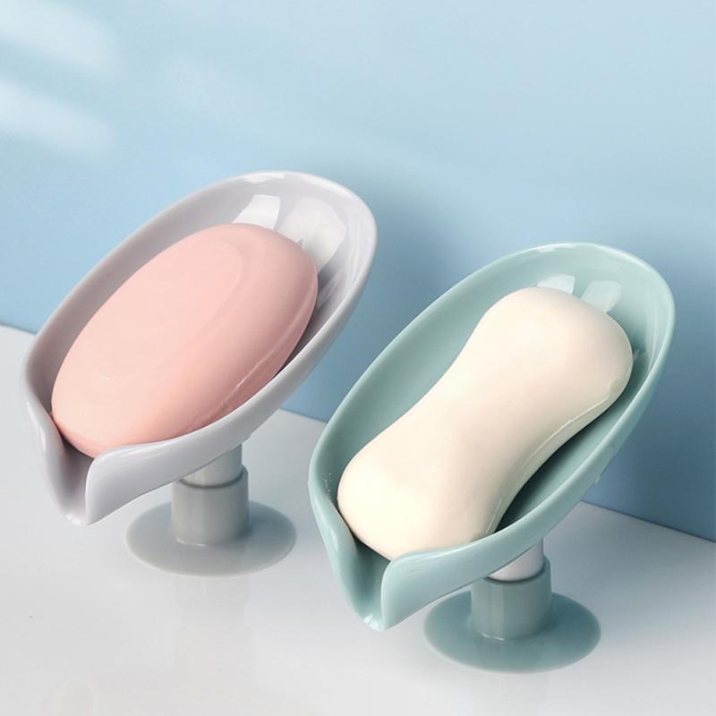 Saboneteira plástica com ventosa e sabonetes branco e rosa sobre superfície branca