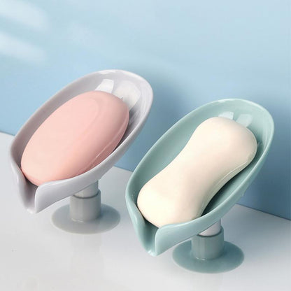 Saboneteira plástica com ventosa e sabonetes branco e rosa sobre superfície branca