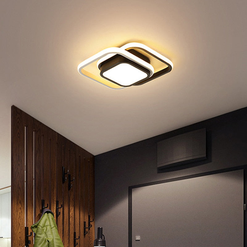 Luminária de teto moderna quadrada com luz branca iluminando ambiente com parede escura e cabideiro de madeira