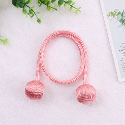 Cortina rosa com bolas de tecido decorativa em fundo branco com folhas verdes