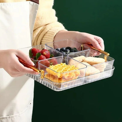 Bandeja multifuncional transparente com potes organizadores contendo morangos, mirtilos, biscoitos e massas em mãos com avental