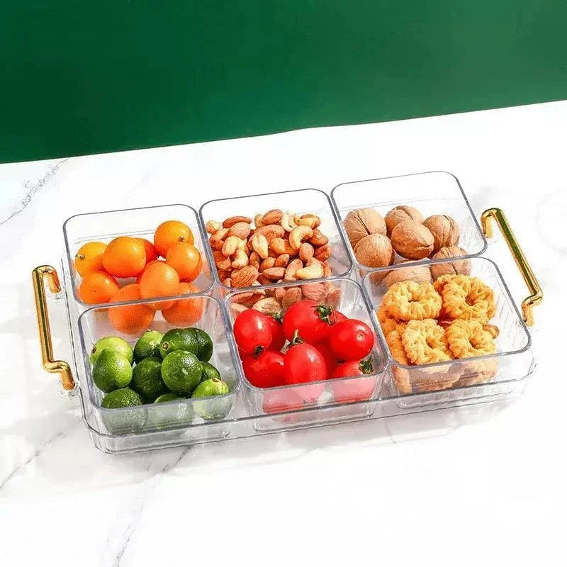 Bandeja multifuncional transparente com potes organizadores contendo frutas, castanhas e biscoitos em mesa branca