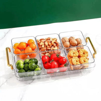 Bandeja multifuncional transparente com potes organizadores contendo frutas, castanhas e biscoitos em mesa branca