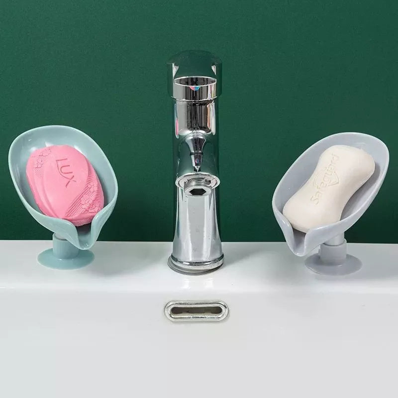 Sabonetes Lux rosa e SpaDiva branco em suportes plásticos ao lado de torneira cromada em pia branca com fundo verde