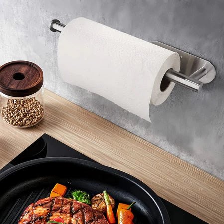 Porta papel toalha de aço inox fixado na parede cinza na cozinha com bancada de madeira e comida na frigideira