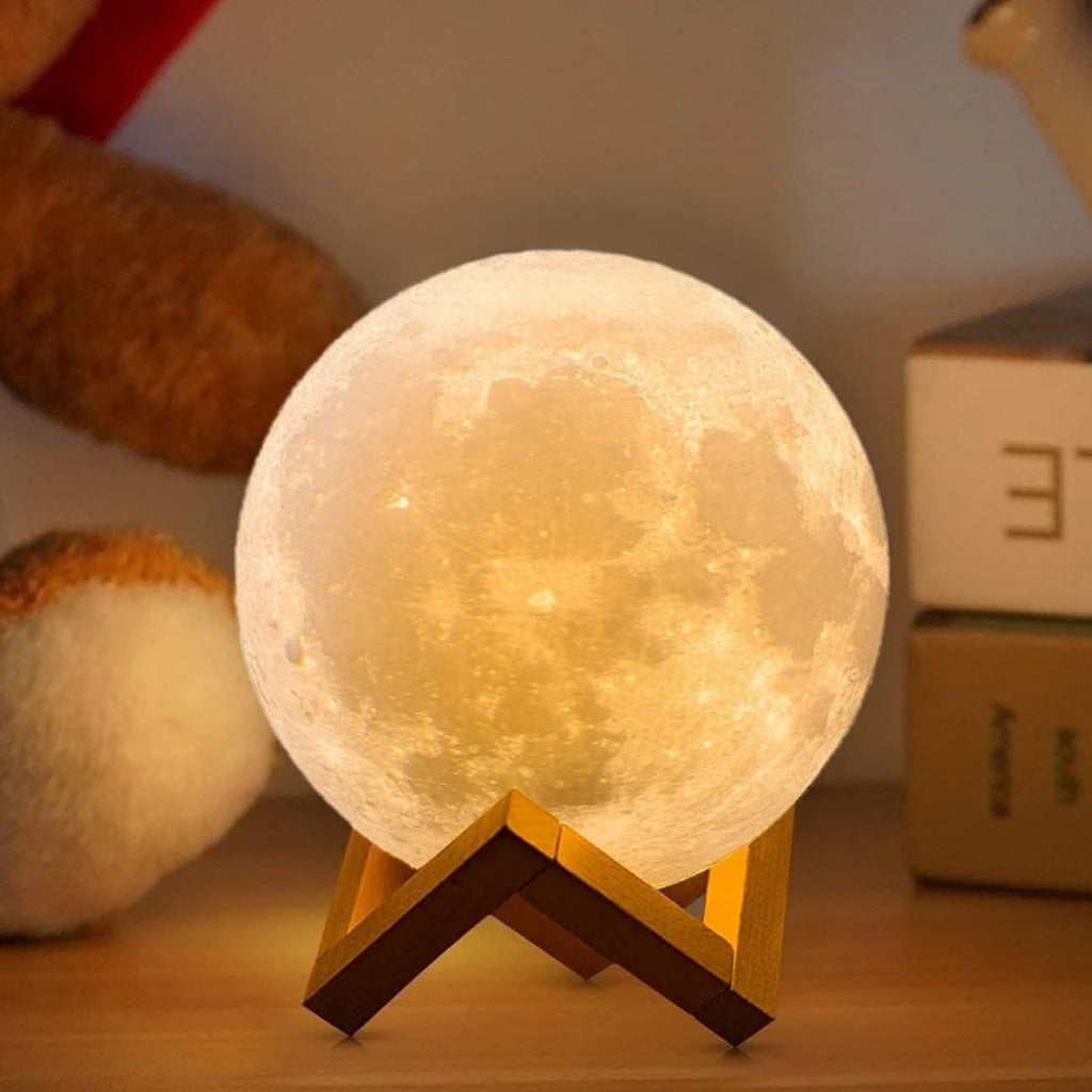 Luminária 3D em forma de lua brilhando em suporte de madeira sobre mesa com livros ao fundo