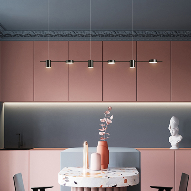 Cozinha moderna com armários rosa, luminárias pendentes e mesa de pedra com vasos decorativos