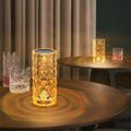 Lâmpadas de cristal iluminadas com design facetado sobre mesas redondas em ambiente com cortinas