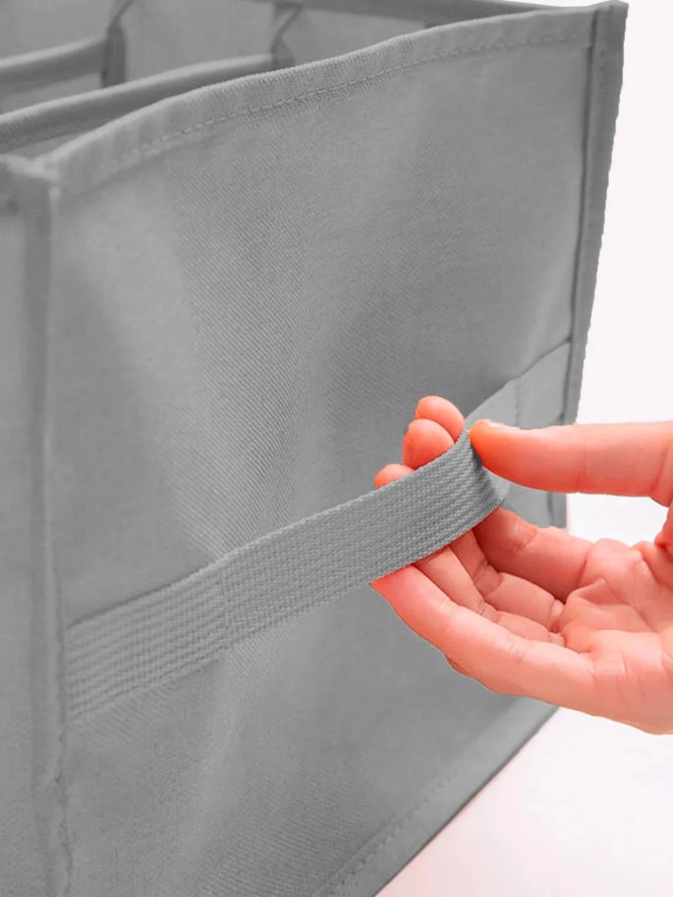 Mão segurando alça de tecido cinza de organizador de roupas modular