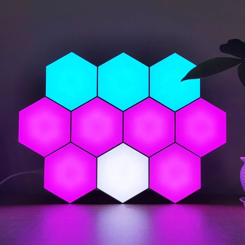 Painel de parede hexagonal com luzes LED coloridas azul, rosa e branca em mesa de madeira