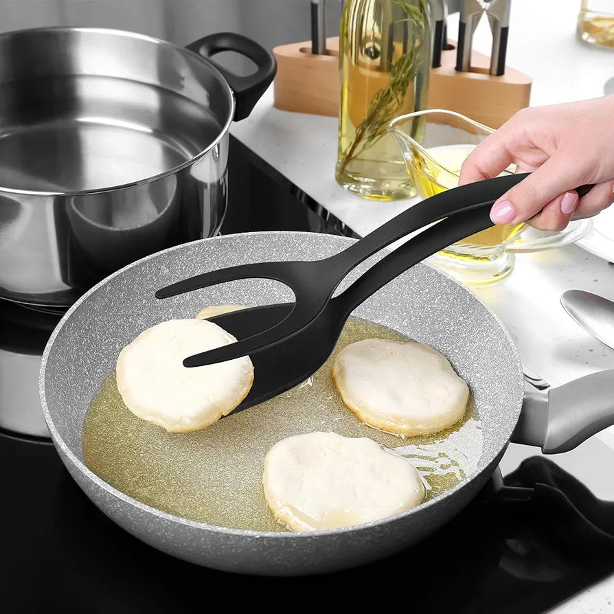 Mão segurando pegador preto virando bolinhos fritando em frigideira cinza na cozinha moderna