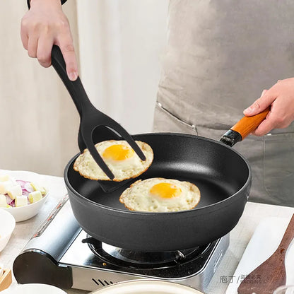Pessoa fritando ovos em frigideira preta com espátula de silicone e fogão portátil