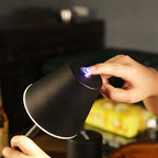 Mão feminina acionando sensor de toque em luminária preta com luz branca