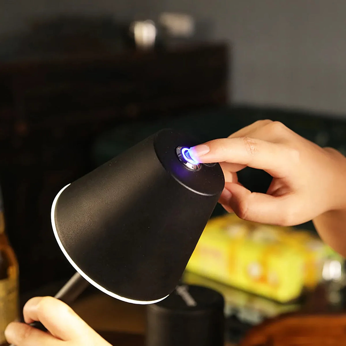Mão feminina acionando sensor de toque em luminária preta com luz branca