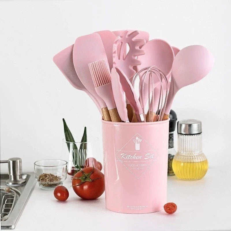 Conjunto de utensílios de cozinha rosa em suporte rosa com ingredientes frescos ao lado