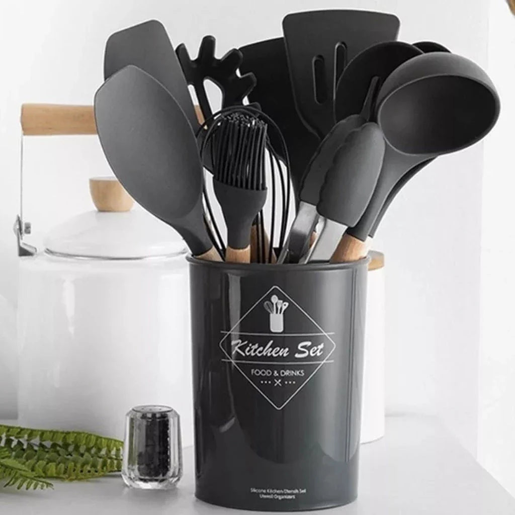 Conjunto de utensílios de cozinha pretos com cabos de madeira em suporte cinza em bancada branca