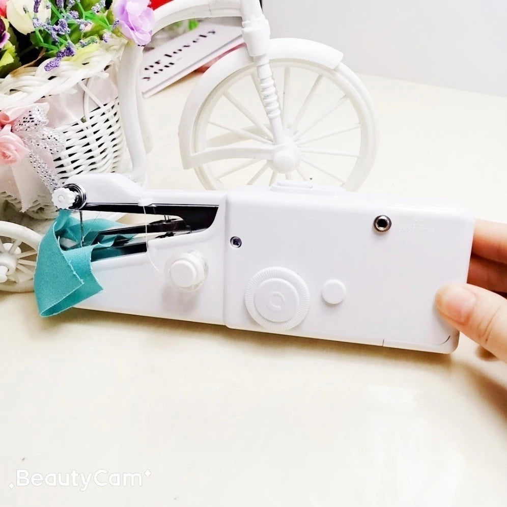 Máquina de costura portátil branca operada com uma mão, tecido azul e decoração com flores e bicicleta branca ao fundo